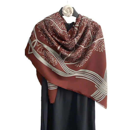 Rust and cream patterned square scarf draped over a black display with a fine fringed edge