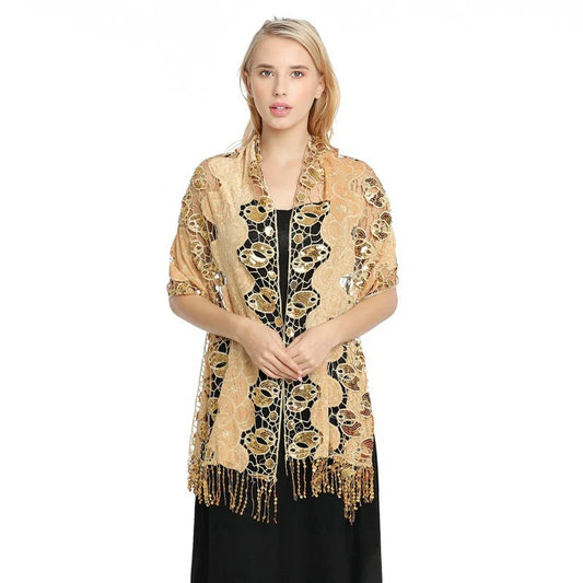 Gold-tone openwork sequin shawl draped over a black dress with long decorative fringe at the front