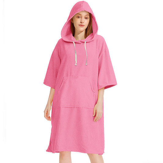 Pink hooded towel poncho shown from the front with loose short sleeves, hood cords and a large front pocket
