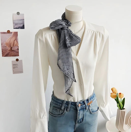 Black-and-white checkered scarf tied in a side bow on a mannequin wearing a white blouse