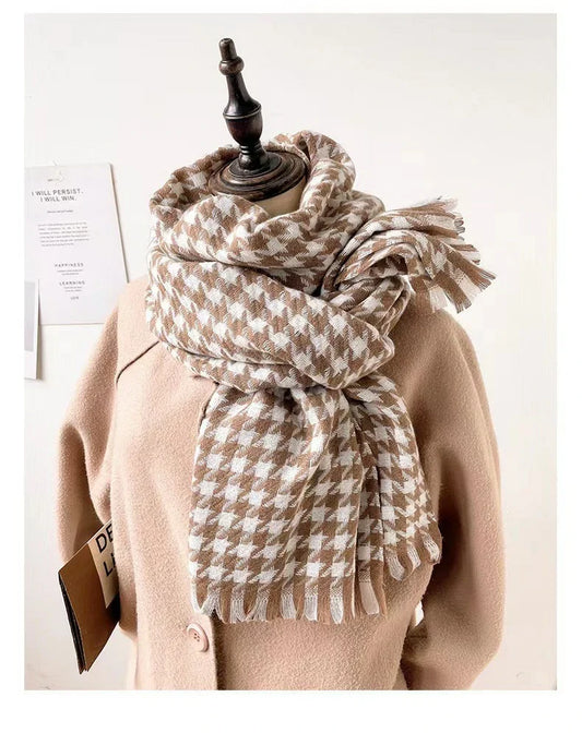 Tan and cream houndstooth scarf looped over a camel coat on a display